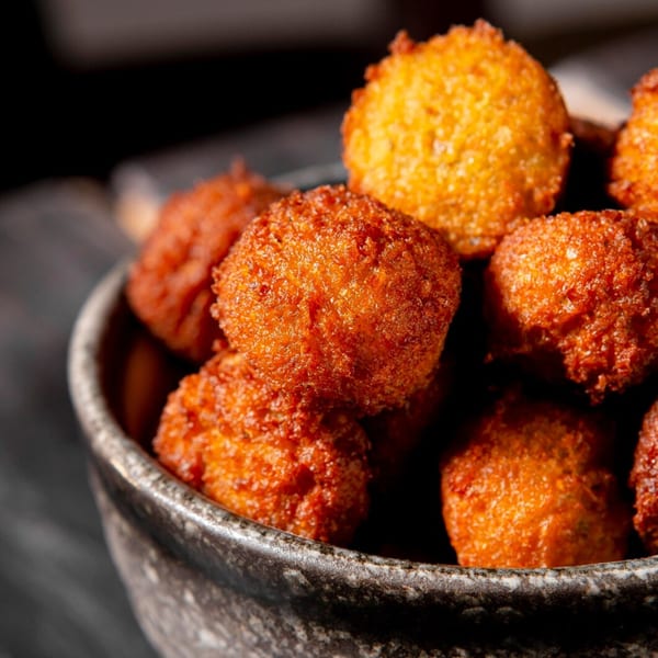 Close-up of a bowl filled with golden-brown, crispy hush puppies from Sharkies Bar & Grill.